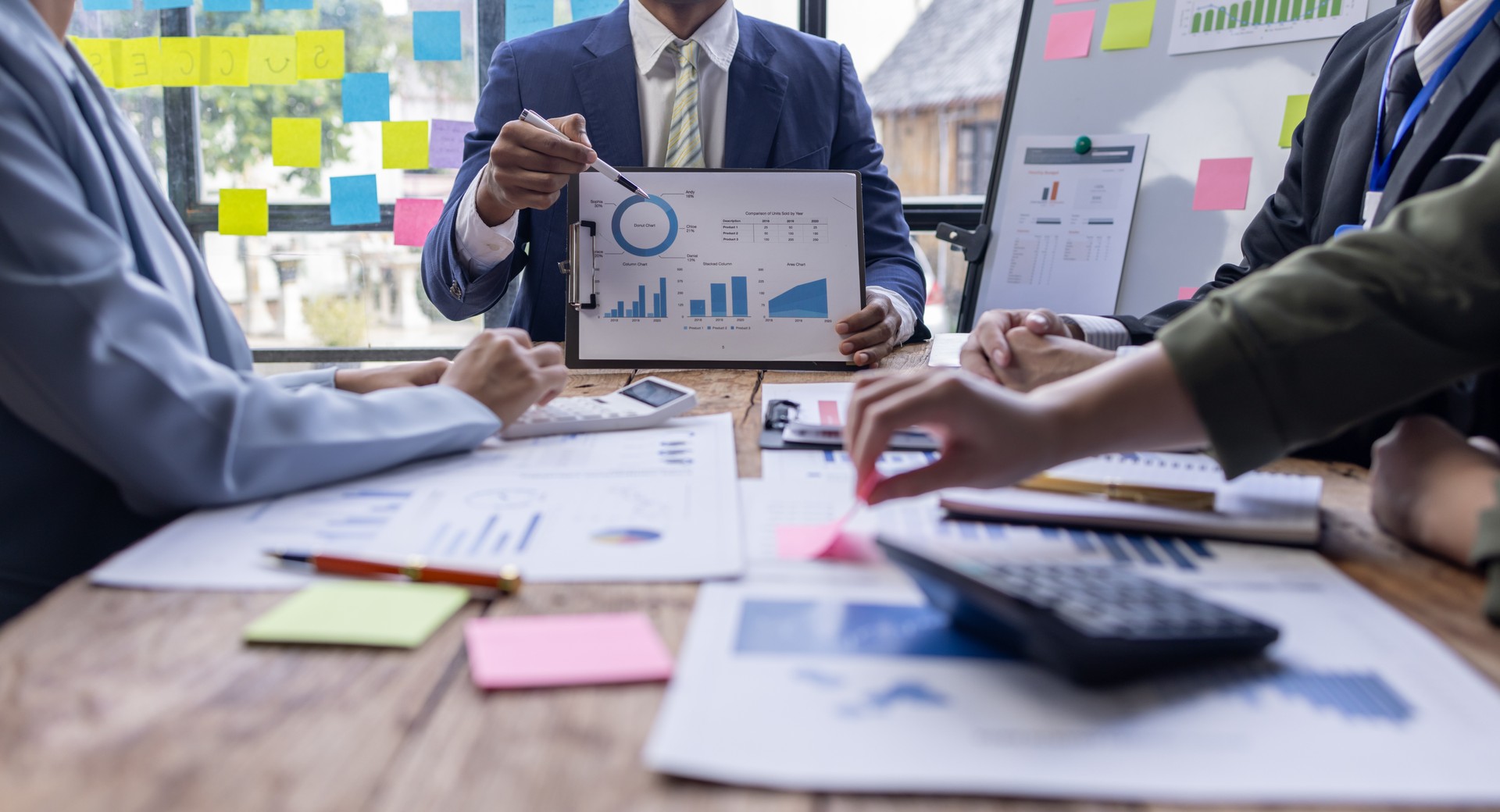 Group of confident business people point to graphs and charts to analyze market data, balance sheet, account, net profit to plan new sales strategies to increase production capacity.